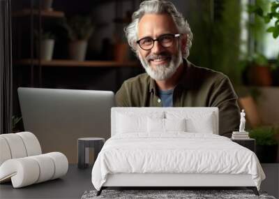 Casual mid adult man with laptop computer at desk in home office, banking online, remote working. Portrait of happy older gray haired bearded guy smiling. Businessman managing business on internet Wall mural