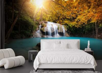 Waterfall in autumn forest with bright sun light and small natural lake with clear blue water Wall mural