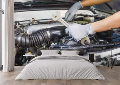 A car mechanic is doing a car repair in a repair shop. Wall mural