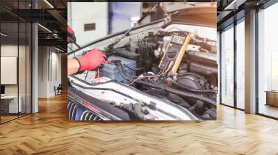 A technician is checking the car battery for availability. Wall mural