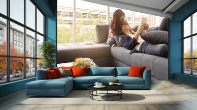 Asian teenage couple make eye contact relaxing on  sofa  by the window relax in the luxurious room. Wall mural