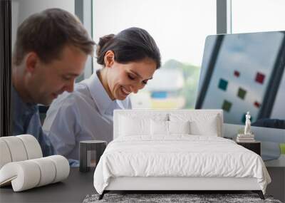 Focus to adult caucasian business woman holding tablet on hand smiling and look feel happy with business men in work office in the morning. On table have computer and more document workpaper Wall mural