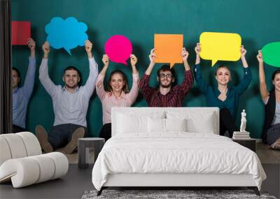 Group of six business people team sittiing together and holding colorful and different shapes of speech bubbles Wall mural