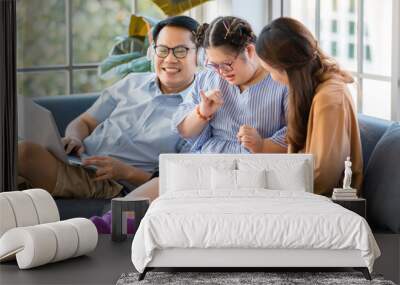 happy Asian family father mother and handicapped down syndrome child sitting on a couch relaxedly in a living room at home. The daughter learning how to count a number Wall mural