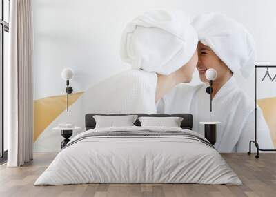 Mom and daughter wearing spa dress talking and teasing with happiness in spa with white cloth and towel-covered around head. Idea for health care and relaxing and family relationship Wall mural