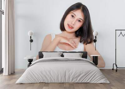 Portrait beauty shot, close up of millennial Asian short black hair model with makeup red lip in tank top undershirt sitting at table posing look at camera on white background Wall mural