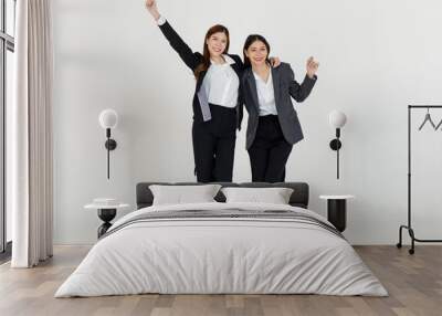 Portrait isolated cutout studio full body shot two Asian professional successful female businesswomen in formal suit standing smiling holding arms smiling together look at camera on white background Wall mural