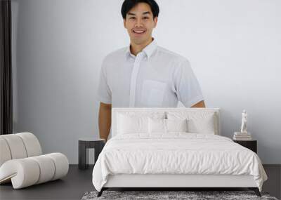 Portrait of Asian young and handsome businessman in casual shirt and slack trousers posing in advertising gesture with friendly and positive isolated on white background Wall mural