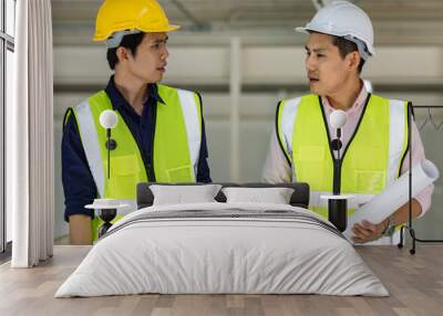 Portrait of young and handsome two Asian male engineers in yellow protective vest working and taking with intimated gesture in factory Wall mural