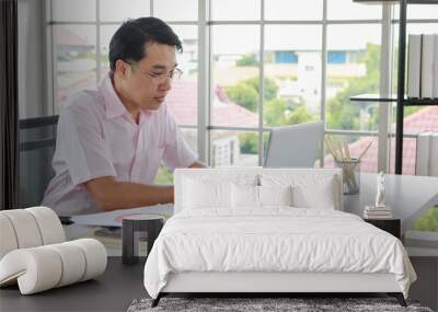 Serious ethnic businessman working on laptop in office Wall mural