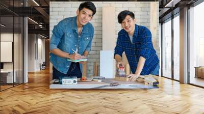 Two good looking Asian carpenter working together for DIY jobs in carpenter room with several kinds of woods and types of equipment Wall mural