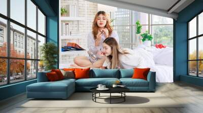 Two happy beautiful Asian female girlfriends cosmetics make face take care of skin beauty products, Pretty woman looking at mirror relaxed on a white bed, Concept teenage or friends lifestyle at home. Wall mural