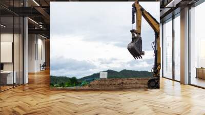 A mini excavator is digging the soil in the field. Wall mural