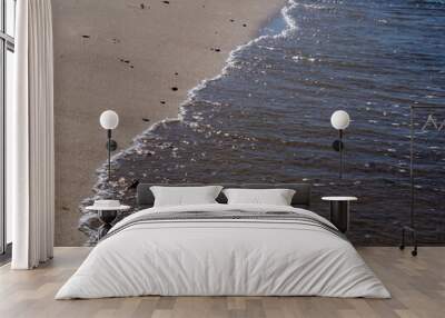 The wave washes the stones and sand on the beach. Wall mural