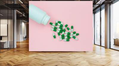 Multicolored tablets, pills, capsules in plastic bottle on pink background, copy space. Heap of assorted various medicine tablets and pills, vitamin and nutritional supplements concept. Wall mural