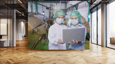 Two asian factory workers use laptop to check process of beverage industry machine Wall mural