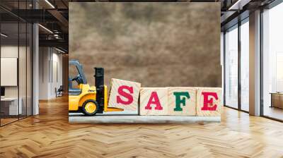 Yellow toy forklift hold letter block S to complete word safe on wood background Wall mural