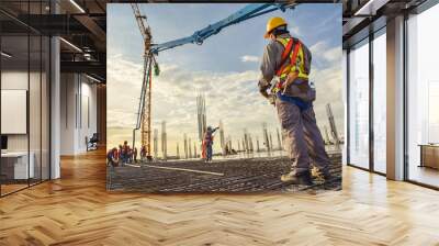 A construction worker control a pouring concrete pump on construction site and sunset background Wall mural