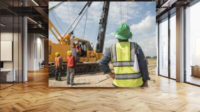 Engineer and foreman looking at heavy machine Assembly concrete pile driving truck  for  working against building construction crane Wall mural