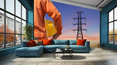 engineer holding yellow helmet standing on silhouette high voltage post.High-voltage tower sky background. Wall mural