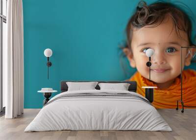 Small cute smiling indian girl with bindi over teal background. Banner with copy space. Shallow depth of field. Wall mural