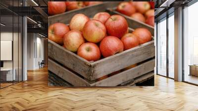 Freshly harvested apples stacked in rustic wooden crates, showcasing their vibrant colors and appealing natural shine. Wall mural