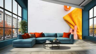 Partial hand wiping a surface with a cleaning cloth, bottle of cleaner in the background, house cleaning, supplies Wall mural