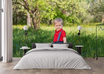 smart little boy walks in the park among the trees Wall mural