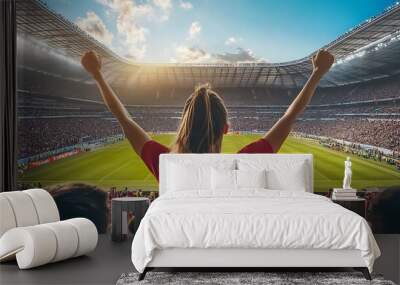 A female fan celebrates with raised arms at a packed soccer stadium. Wall mural