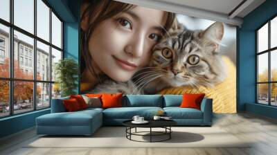 Asian woman playing with adorable fluffy British Shorthair cat in yellow sweatshirt on sofa at home, Happy young girl hugging cute grey pet kitten in modern living room Wall mural