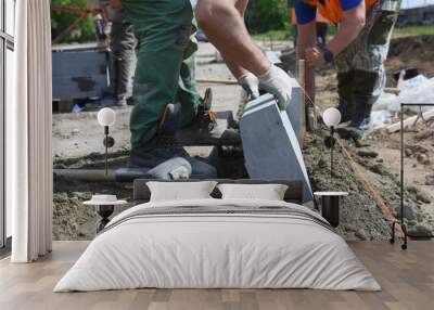 Close-up of workers installing concrete curbs in cement along an asphalt road, building a highway. Wall mural