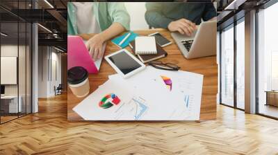 business team analyzing marketing strategy with smart phone, tablet, notebook, and laptop on wooden desk with,Freelance work at home office.Team work and helping hand Wall mural