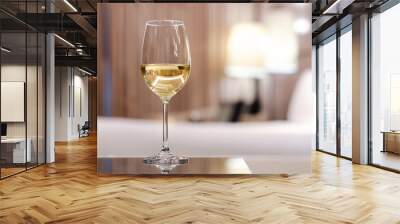 A glass of white wine puts on table in bed room. Relaxing at home concept. Wall mural