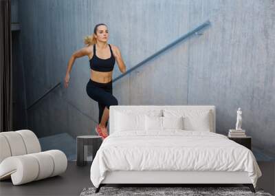 Athletic woman running up stairs Wall mural