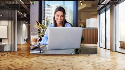 Attractive woman using laptop sitting outside cafe Wall mural