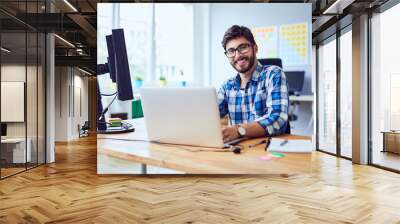 cheerful young programmer looking at camera while working at his office Wall mural