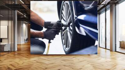 Closeup of car mechanic changing car wheel tire with pneumatic wrench in auto service Wall mural