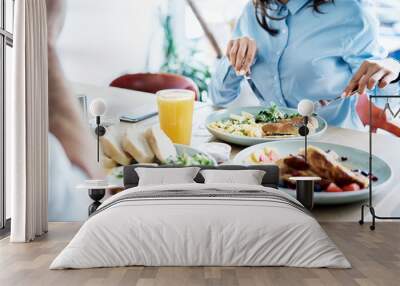 Couple having healthy breakfast in modern restaurant. People eating out together Wall mural