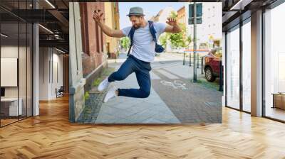 Handsome man dancing jumping on city street Wall mural