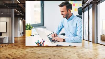 Happy businessman working on laptop at corporate office Wall mural