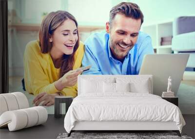 Happy couple doing online shopping with credit card and laptop Wall mural