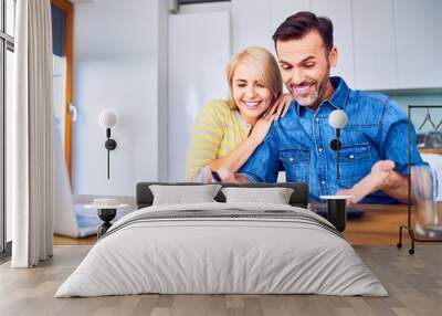 Happy couple looking at notebook in awe while managing home finances Wall mural