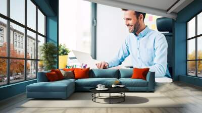 Happy man working on laptop at corporate office Wall mural