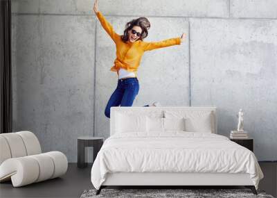 Happy woman jumping against concrete wall in the city Wall mural