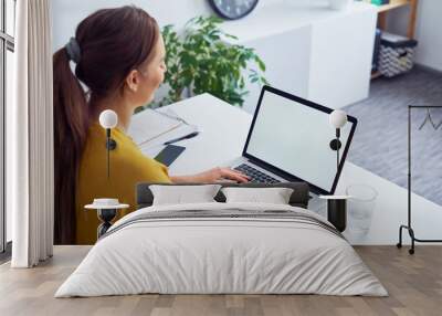 Laptop screen mock-up. Young woman using laptop in office Wall mural