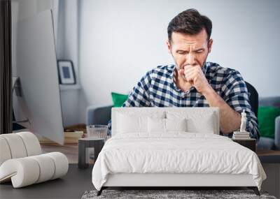 Man coughing while working on a computer from home Wall mural