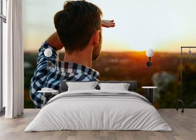 Man standing on meadow in mountains and admiring sunset Wall mural