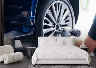 Mechanic changing car wheel in auto service using pneumatic wrench Wall mural