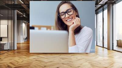 Portrait of a gorgeous young entrepreneur looking and laptop and smiling while in office Wall mural