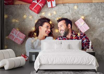 Portrait of cute couple holding presents together in room with christmas decorations Wall mural